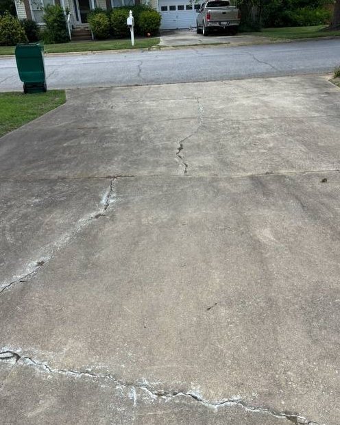 Same driveway before washing, gray with dark staining along the cracks